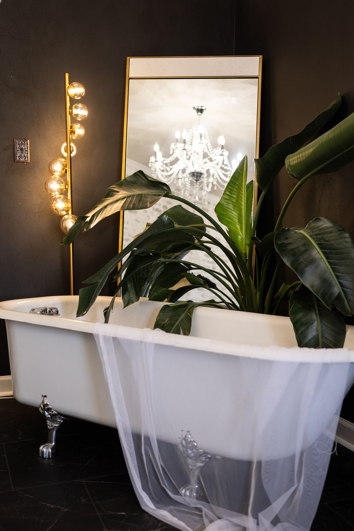 Clawfoot tub with gold globe lights and tropical leaves in LeZandra Photography’s Norfolk boudoir studio