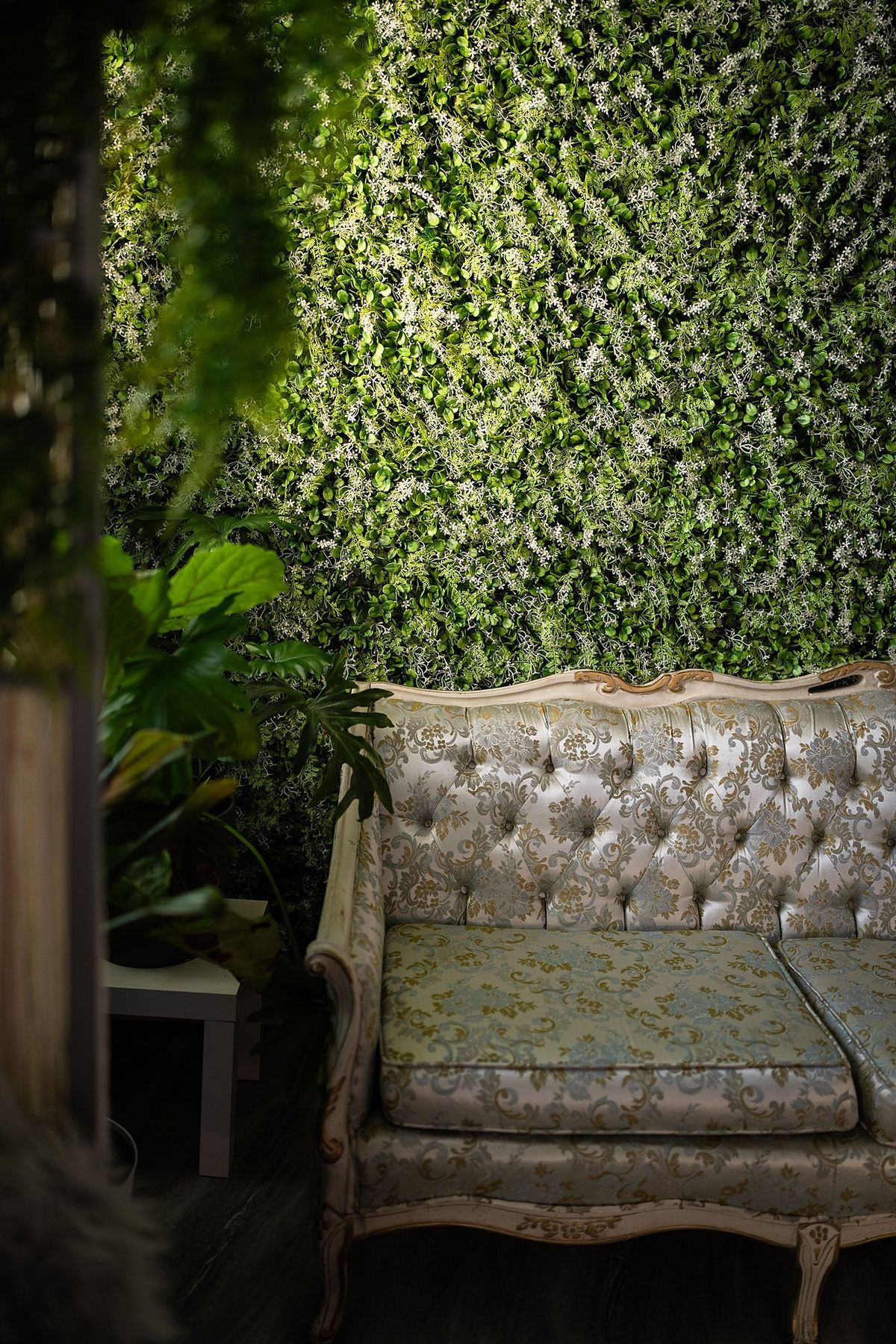 Vintage tufted loveseat against a living garden wall at LeZandra Photography’s Norfolk, Virginia boudoir studio