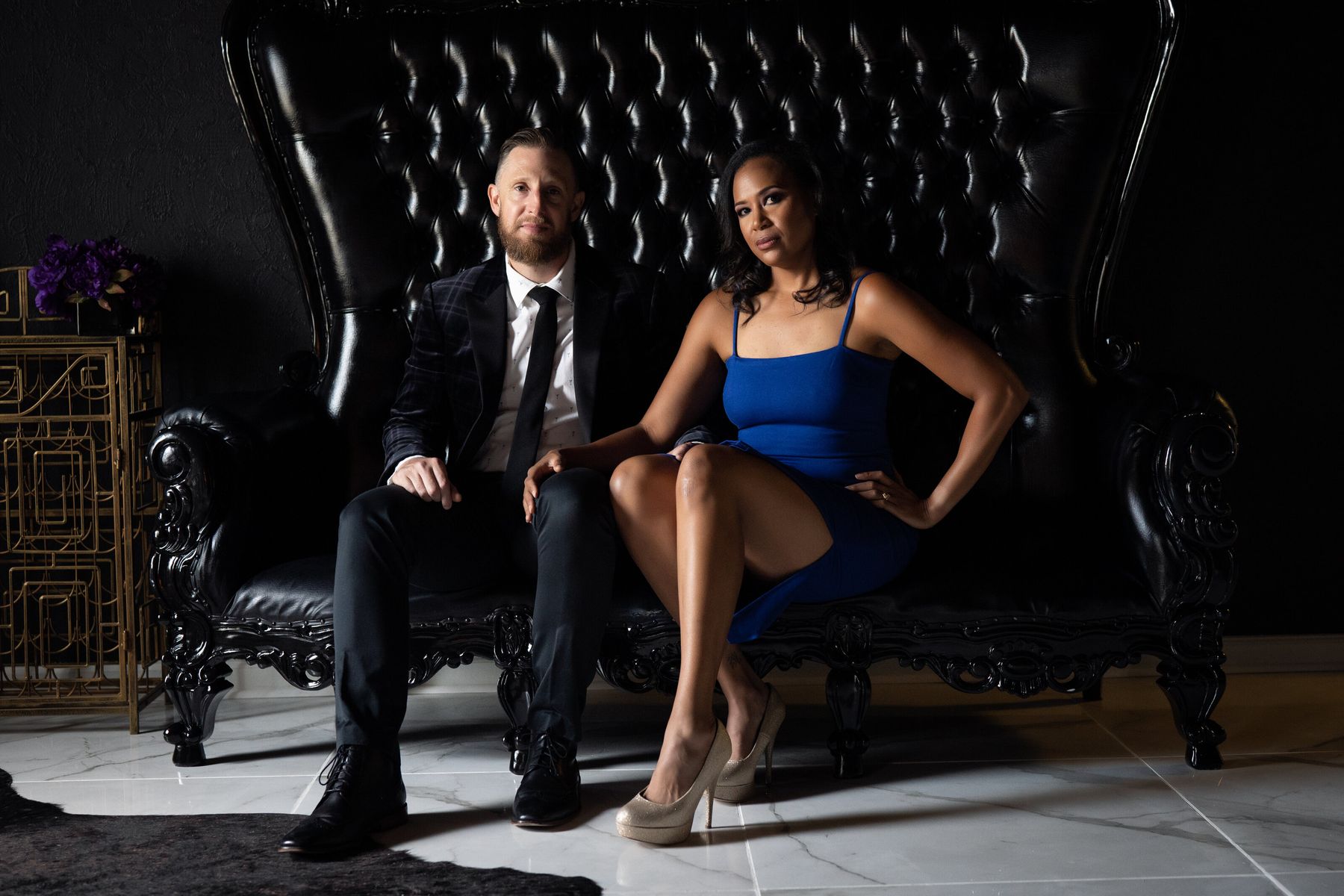 Couple posing on a black tufted leather throne at LeZandra Photography, Norfolk, Virginia couples boudoir photographer