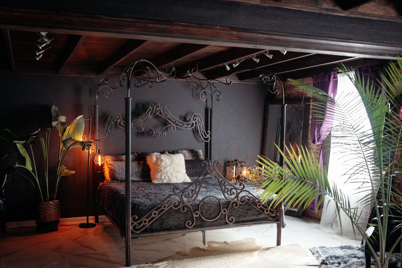 Wrought iron canopy bed beside exposed brick and window light in LeZandra Photography’s Norfolk boudoir studio
