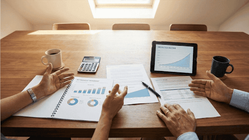 Overhead view of a retirement planning session with financial documents, calculator, and projected income charts showing collaborative strategy Overhead view of a retirement planning session with financial documents, calculator, and projected income charts showing collaborative strategy