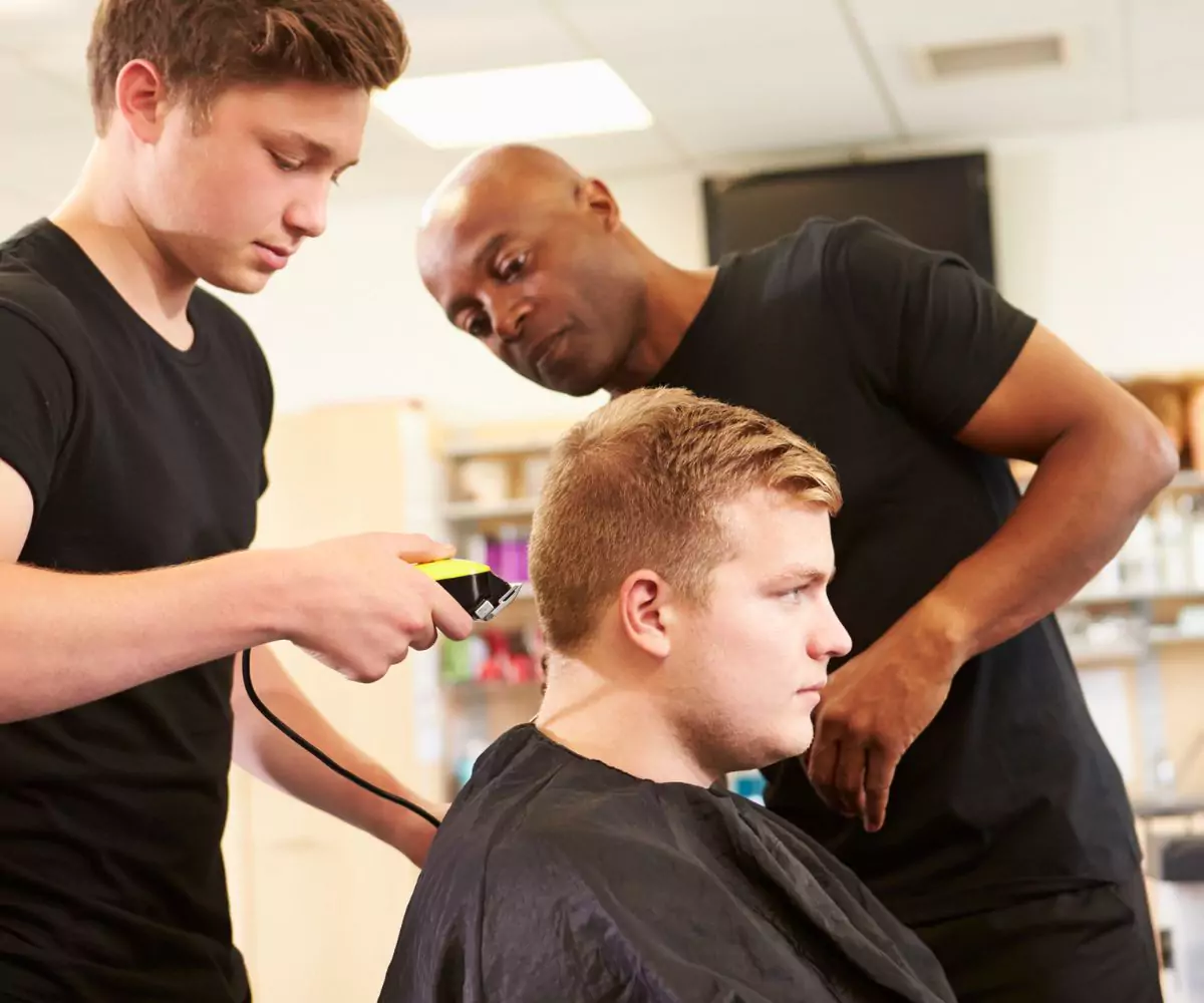 Student observing a hairstylist using clippers at Great Hair in Maine, supervised by an instructor during a job shadowing salon visit.