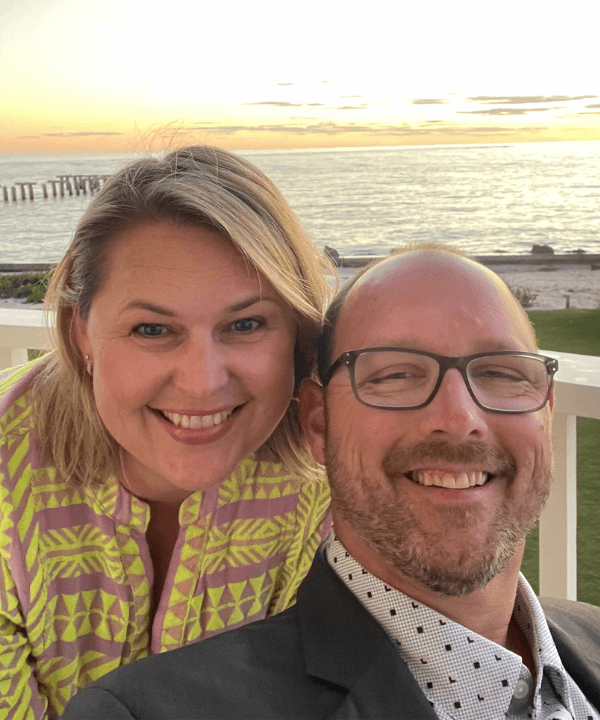 Tim and Hannah Renyi, owners of Great Hair in Maine, smiling together at the beach in casual attire