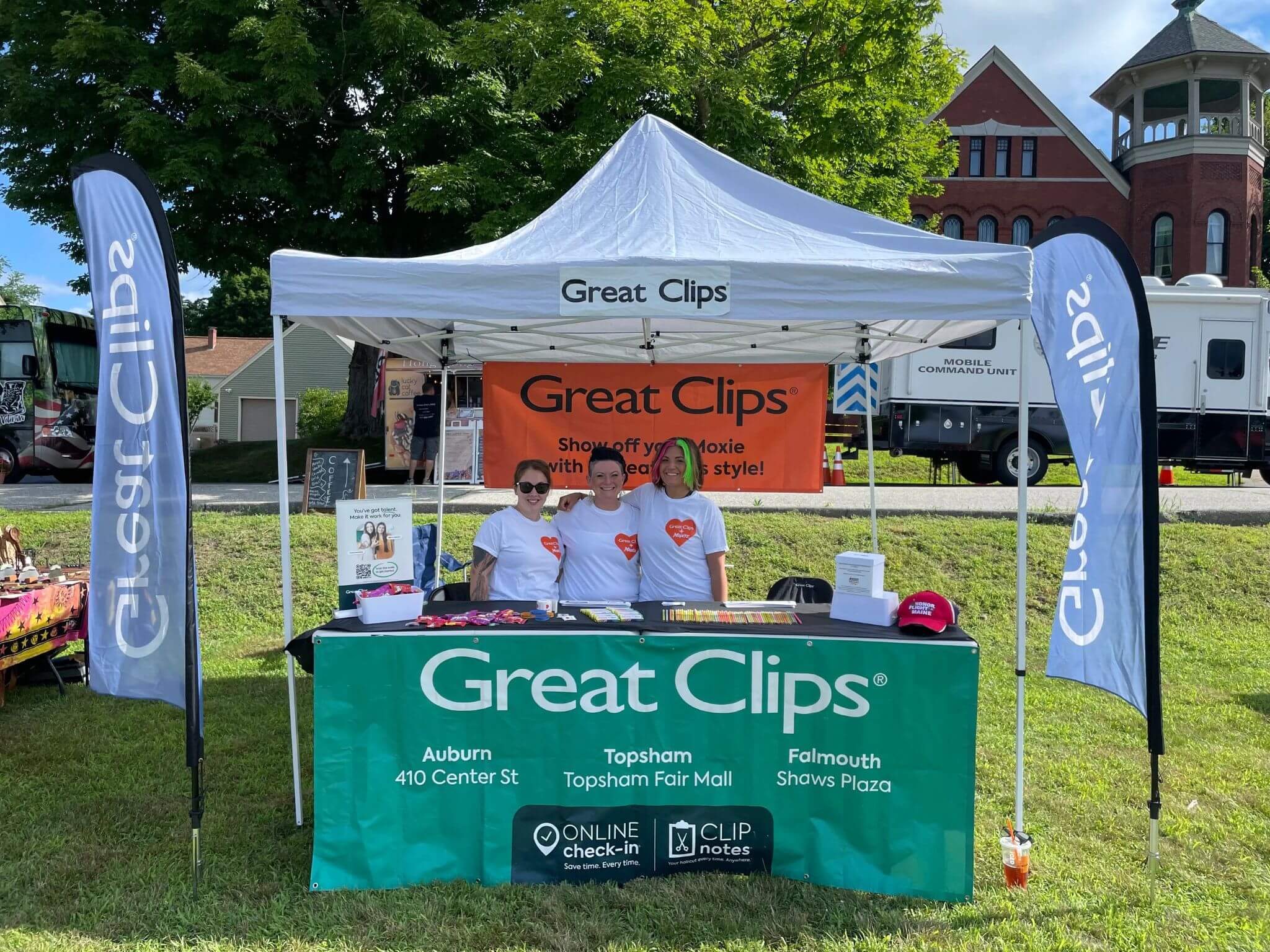 Licensed hairstylists at Great Hair in Maine smiling during at an outdoor booth, reflecting supportive and fun salon culture.