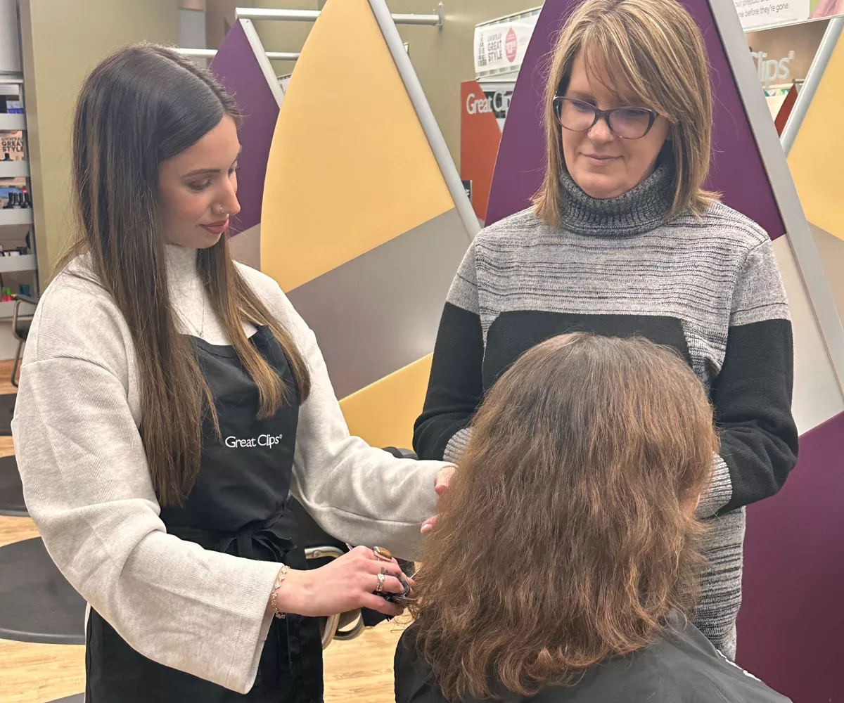 Cosmetology student working on a haircut techniques on a head model to a Maine student at Great Hair in Maine, supporting student training and skill development.