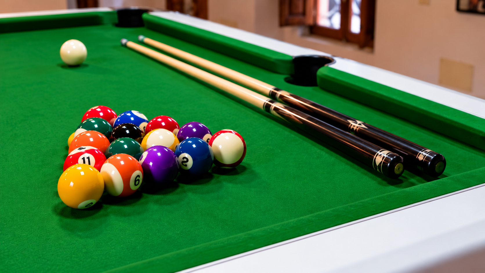 Green English pool table with coloured pool balls, two cues and a centre pocket