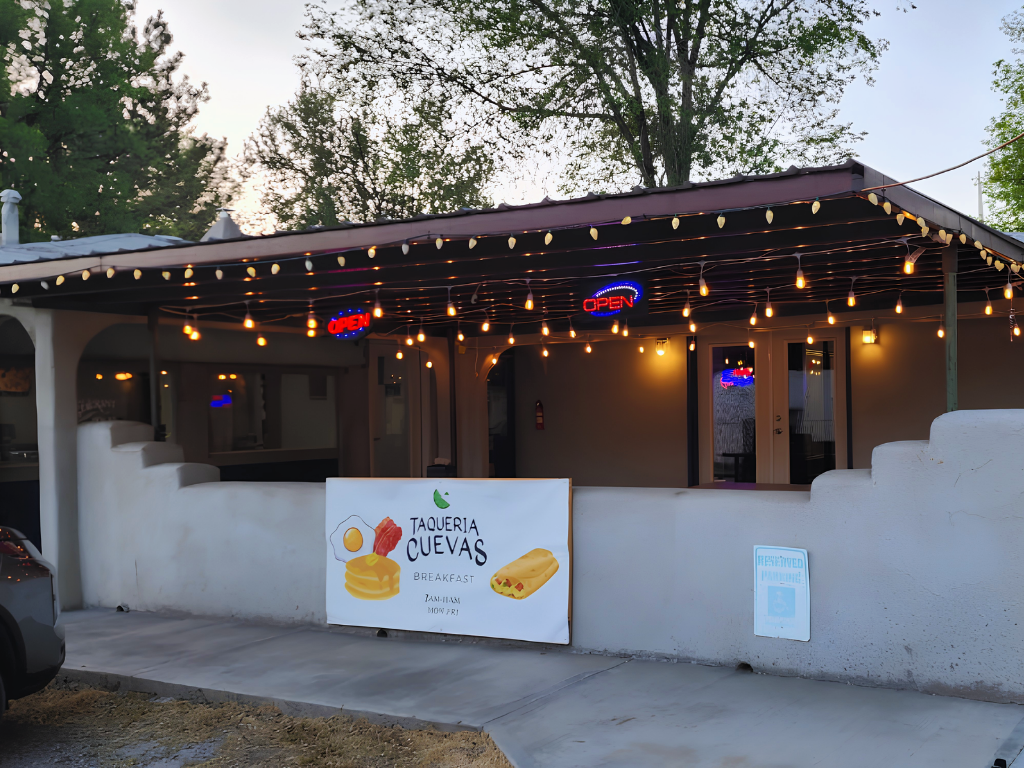 Taqueria Cuevas patio at dusk with string lights and open signs