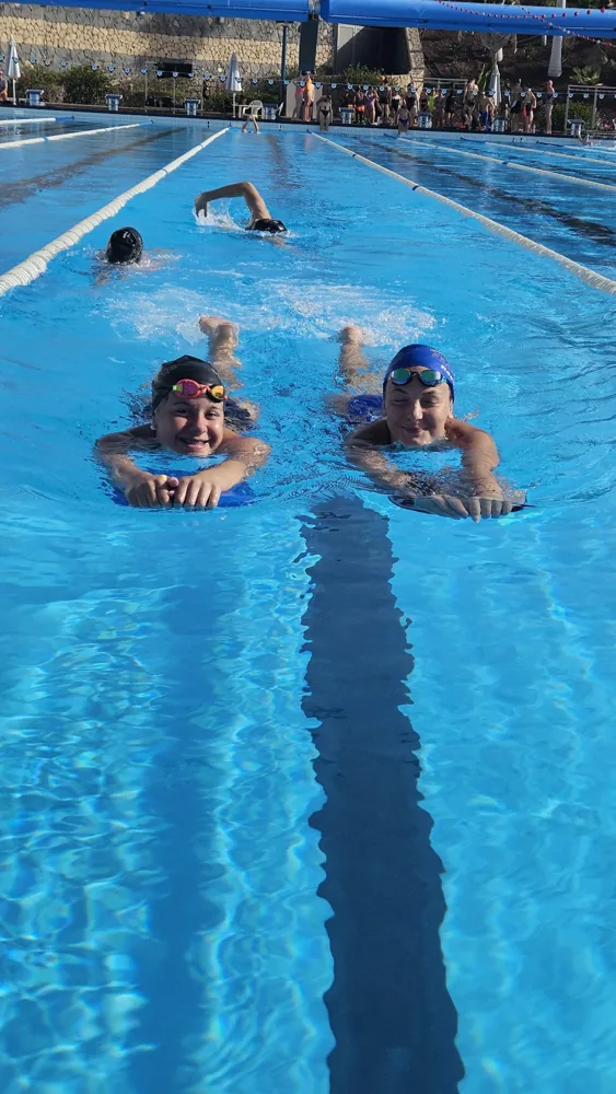 Two young swimmers kicking towards the camera, grinning