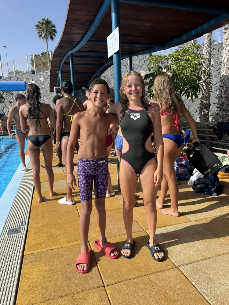 Two young swimmers smiling on the pool deck