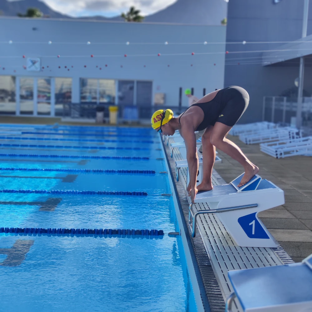Competitive swimmer set on the starting block at the Swimpros camp pool in Tenerife