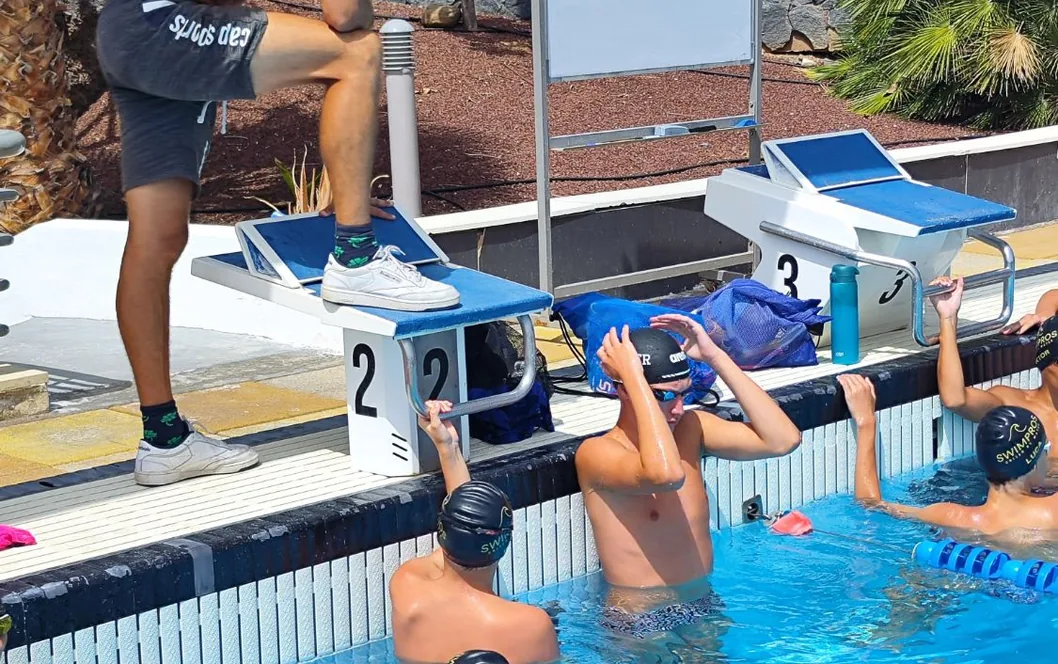 A Swimpros coach talking a junior group through the set from the starting block