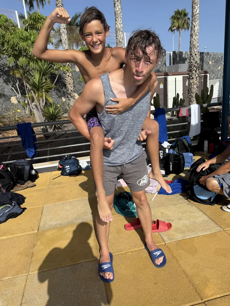 A swimmer carrying a team mate on his back, both laughing