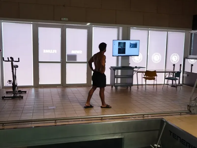 Coach at the video-analysis screen beside the flume