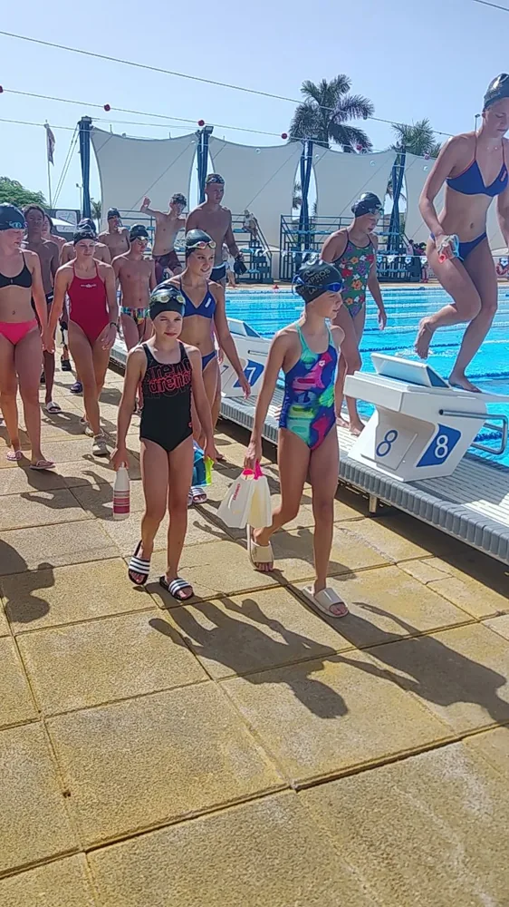 Young swimmers walking along the blocks with their kit