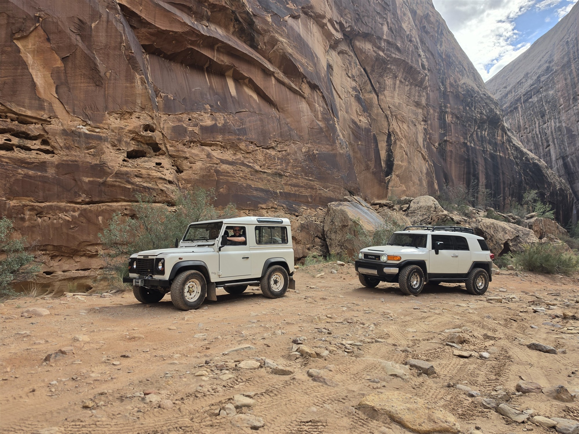 Two off-road vehicles beneath towering Utah canyon walls