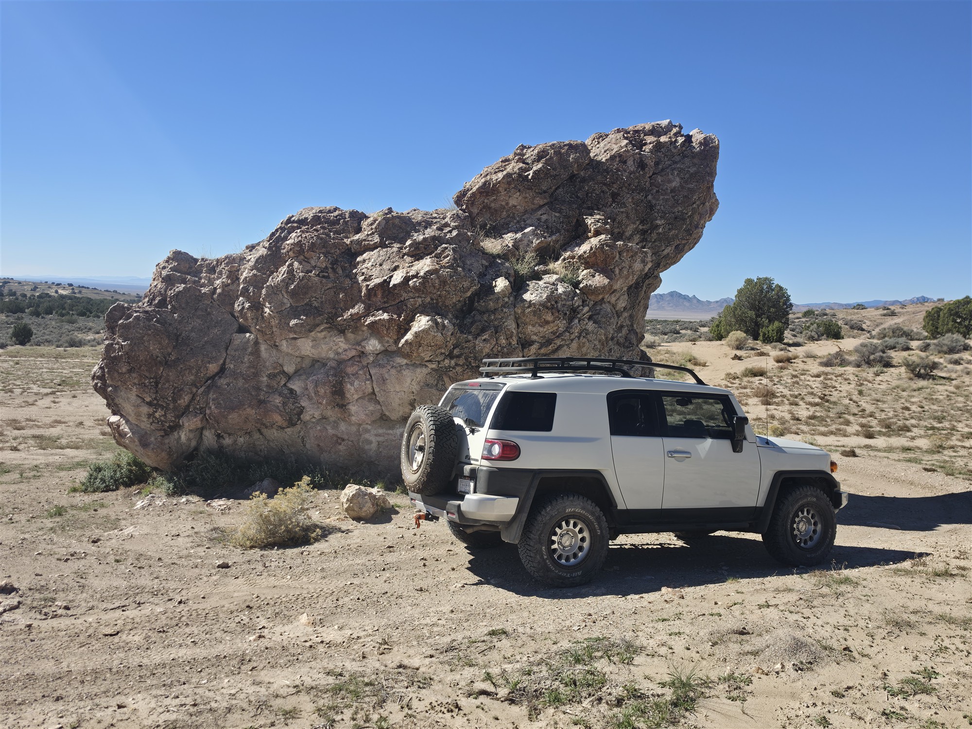 White FJ Cruiser beside a dramatic desert rock formation