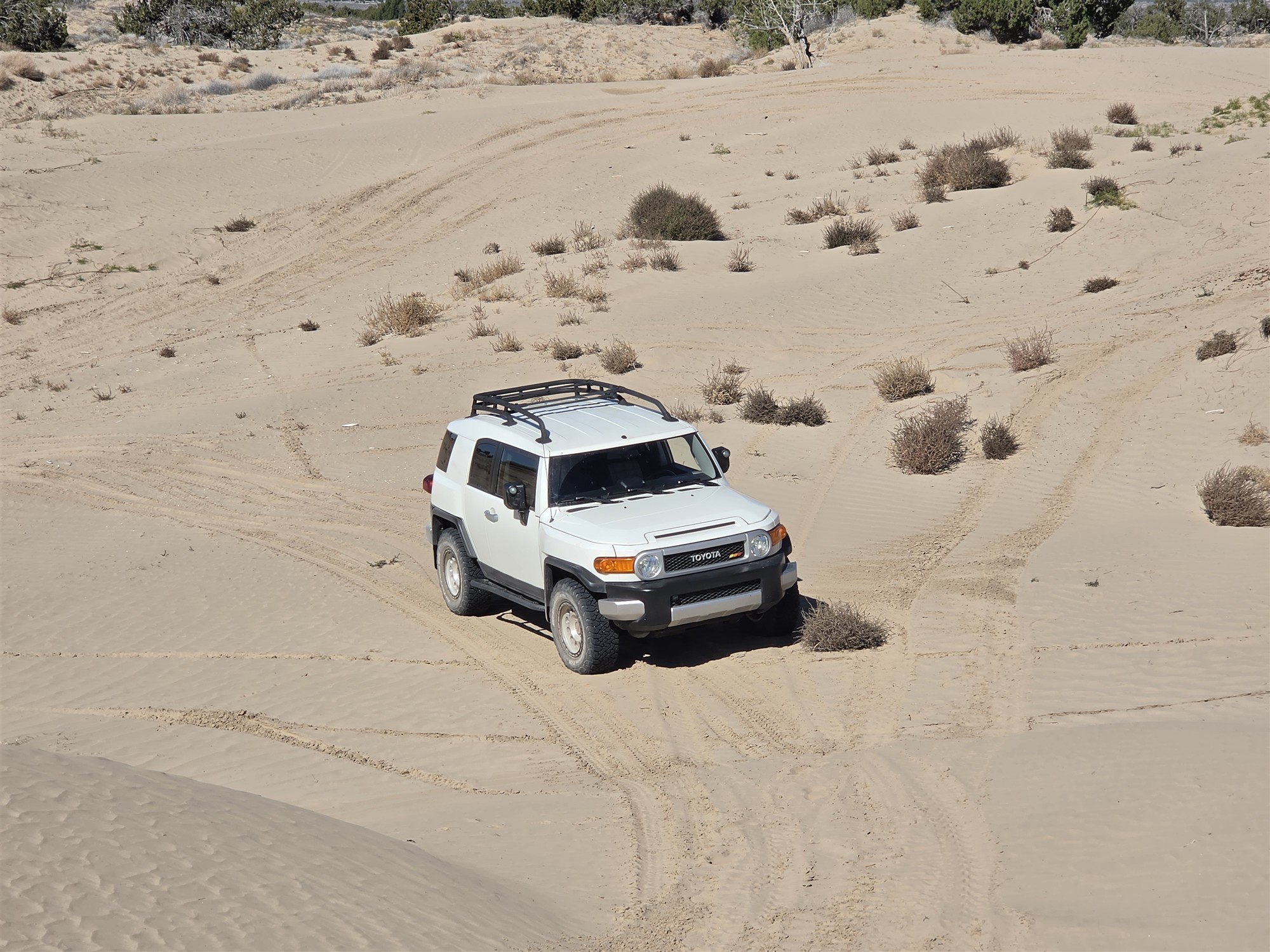 Front three-quarter view of the white Toyota FJ Cruiser in Utah sand