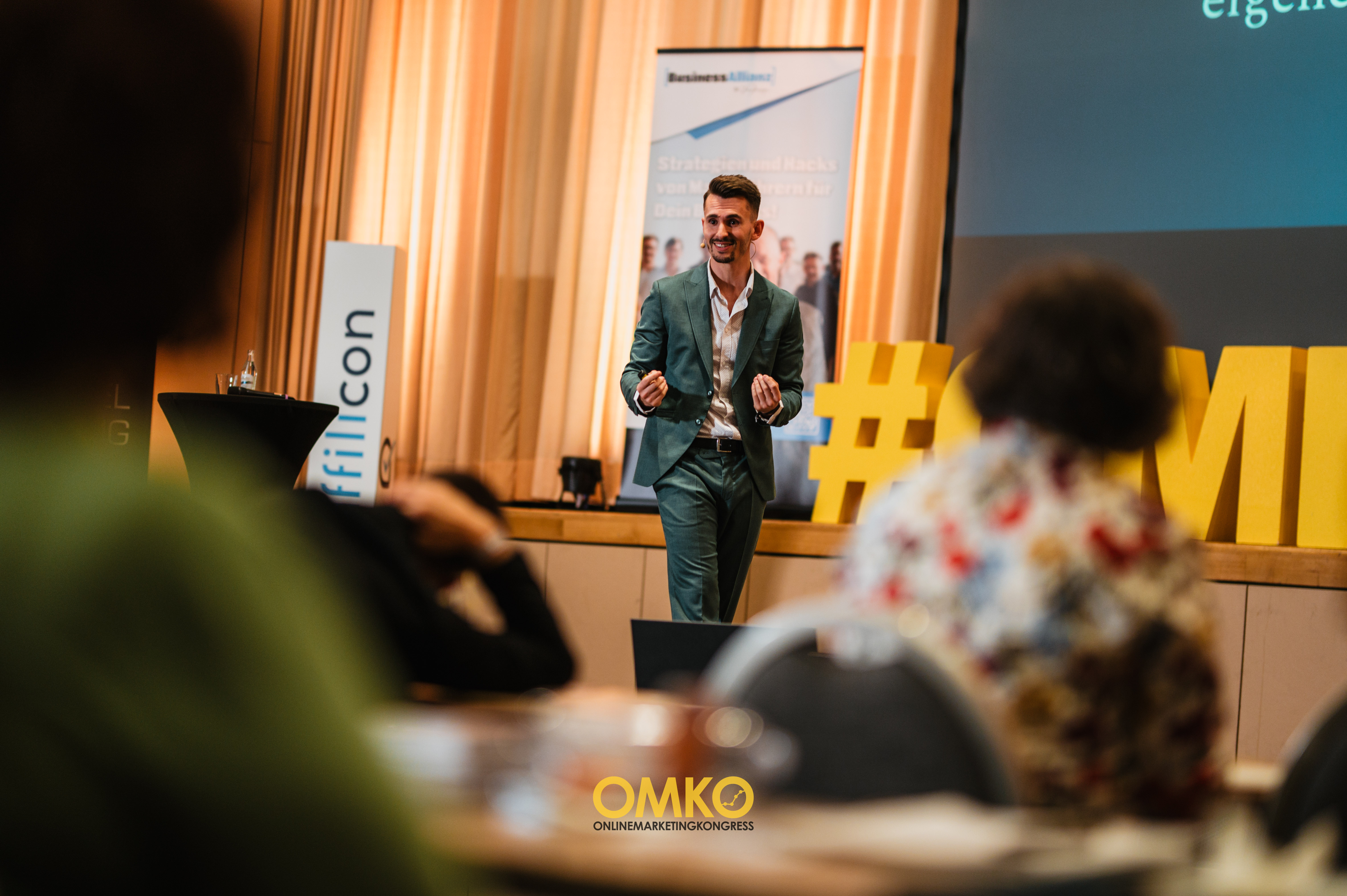 Publikum im Konferenzsaal mit erhobenen Händen