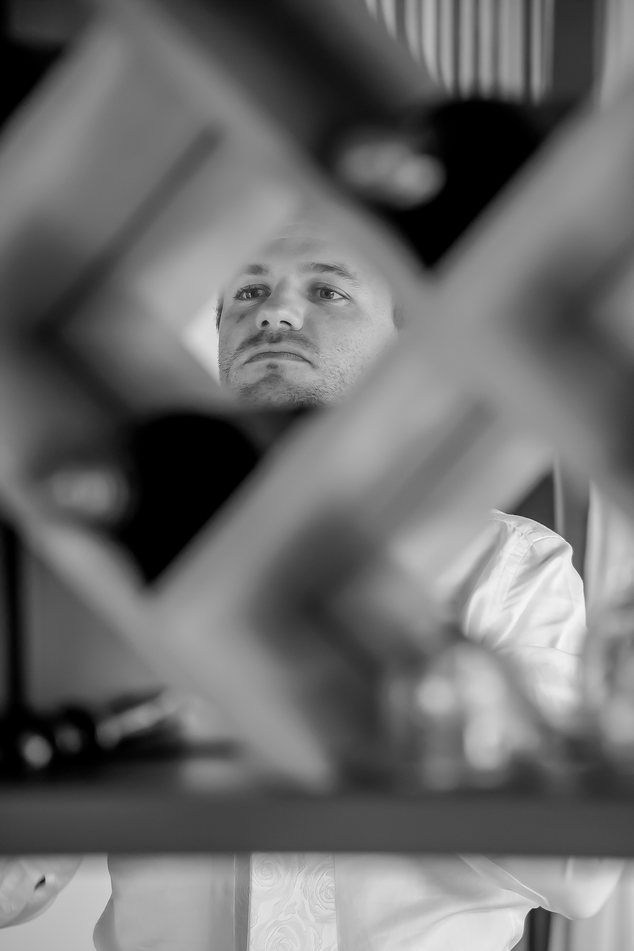 A groom's face caught in a mirror between blurred frames as he gets ready