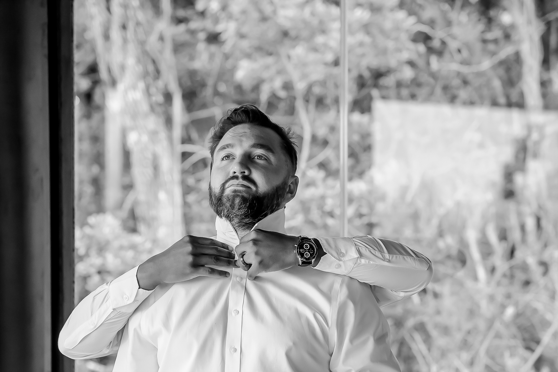 A groom doing up his shirt collar