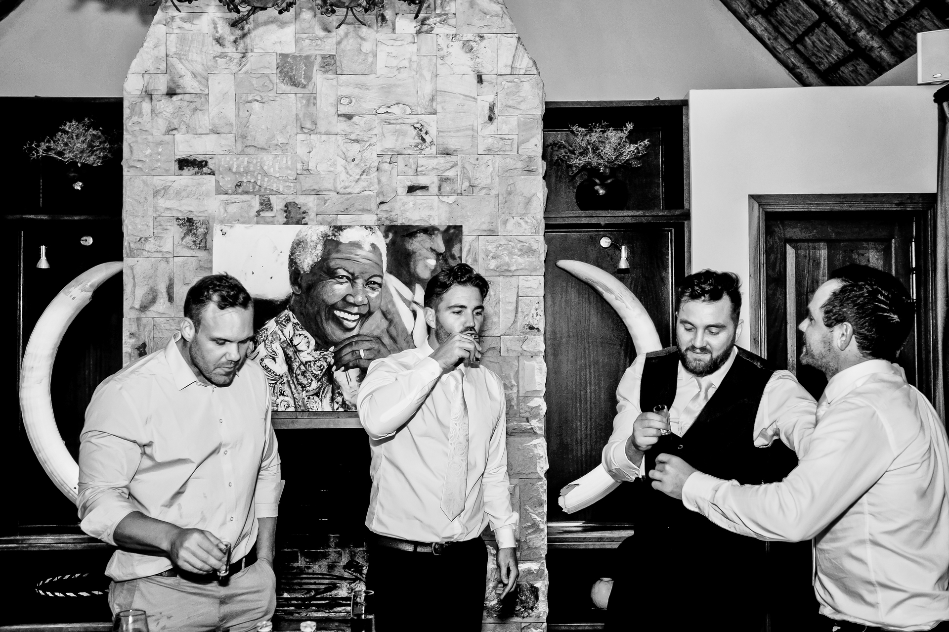 Groomsmen doing shots in front of a stone fireplace