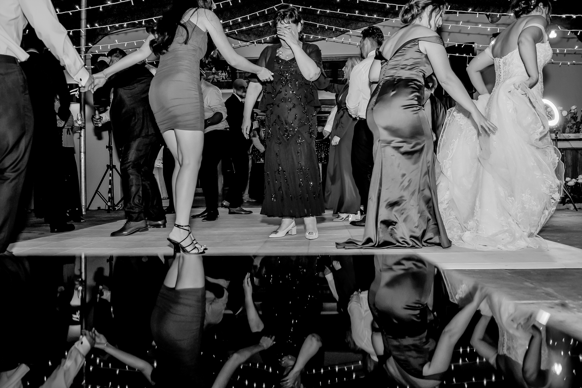 Wedding guests dancing, reflected in the floor below