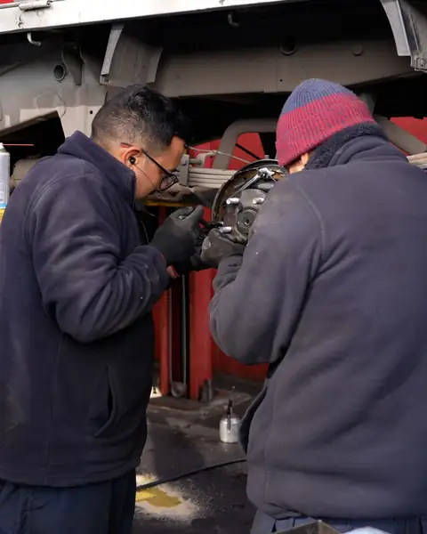 Dos mecánicos de Incubo reparando frenos de una camioneta