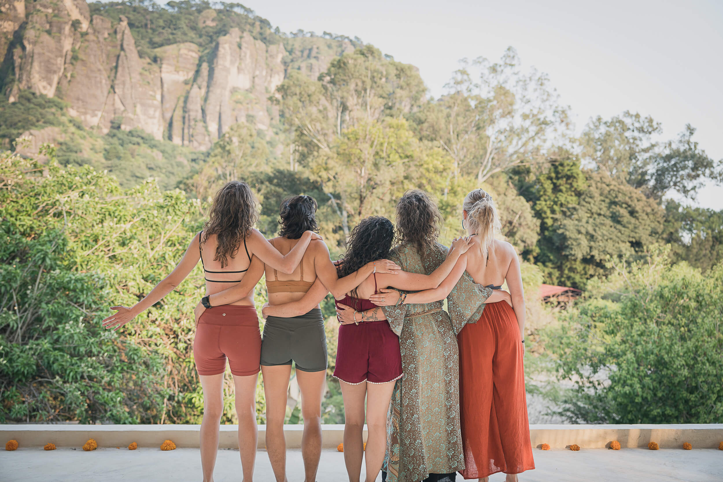 A group of retreat attendees embracing and looking out at a scenic view of towering cliffs and verdant forest, capturing the essence of camaraderie and nature's beauty in lifestyle photography by Matt Anthony Photography.