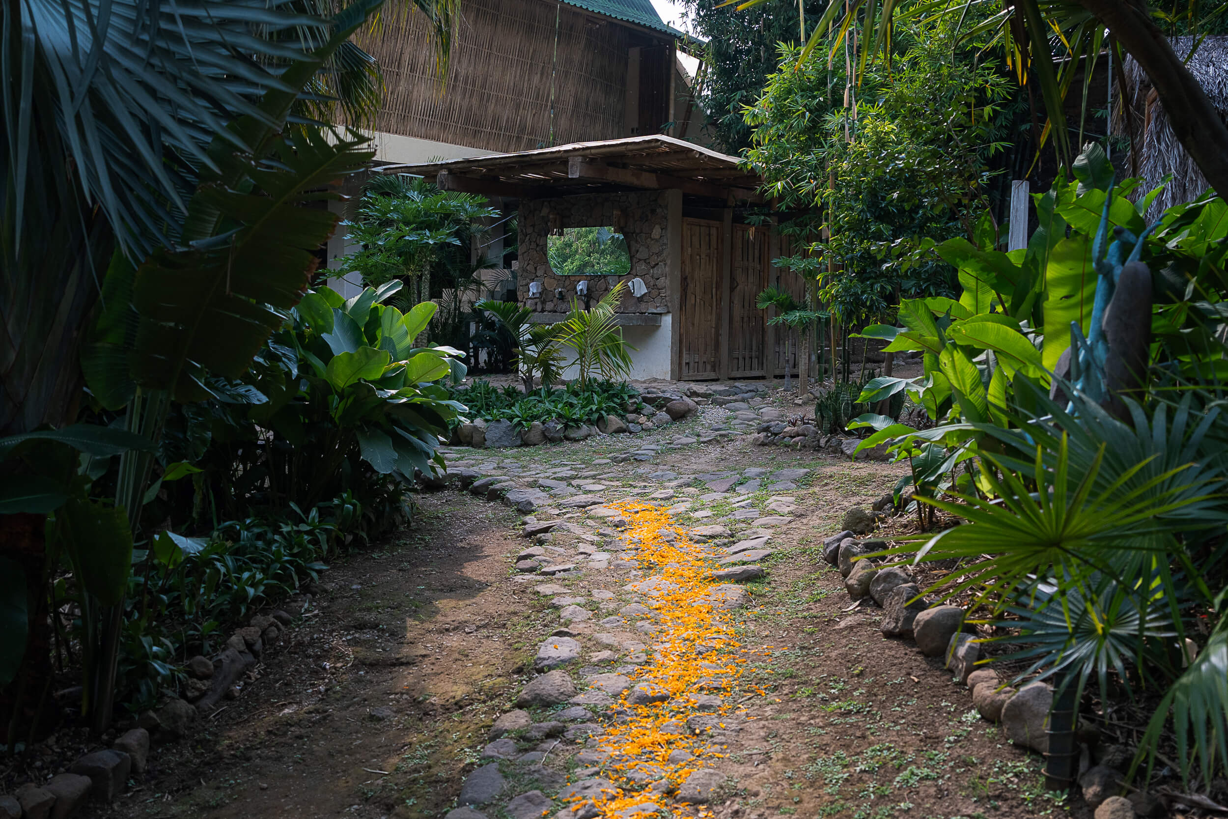 Pathway adorned with marigold petals leading through the gardens at Amate Retreat Centre