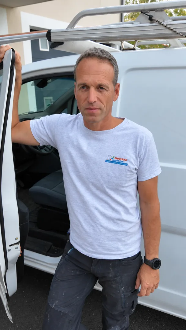 Jean-Michel Enjolras, artisan plombier-chauffagiste devant son véhicule professionnel
