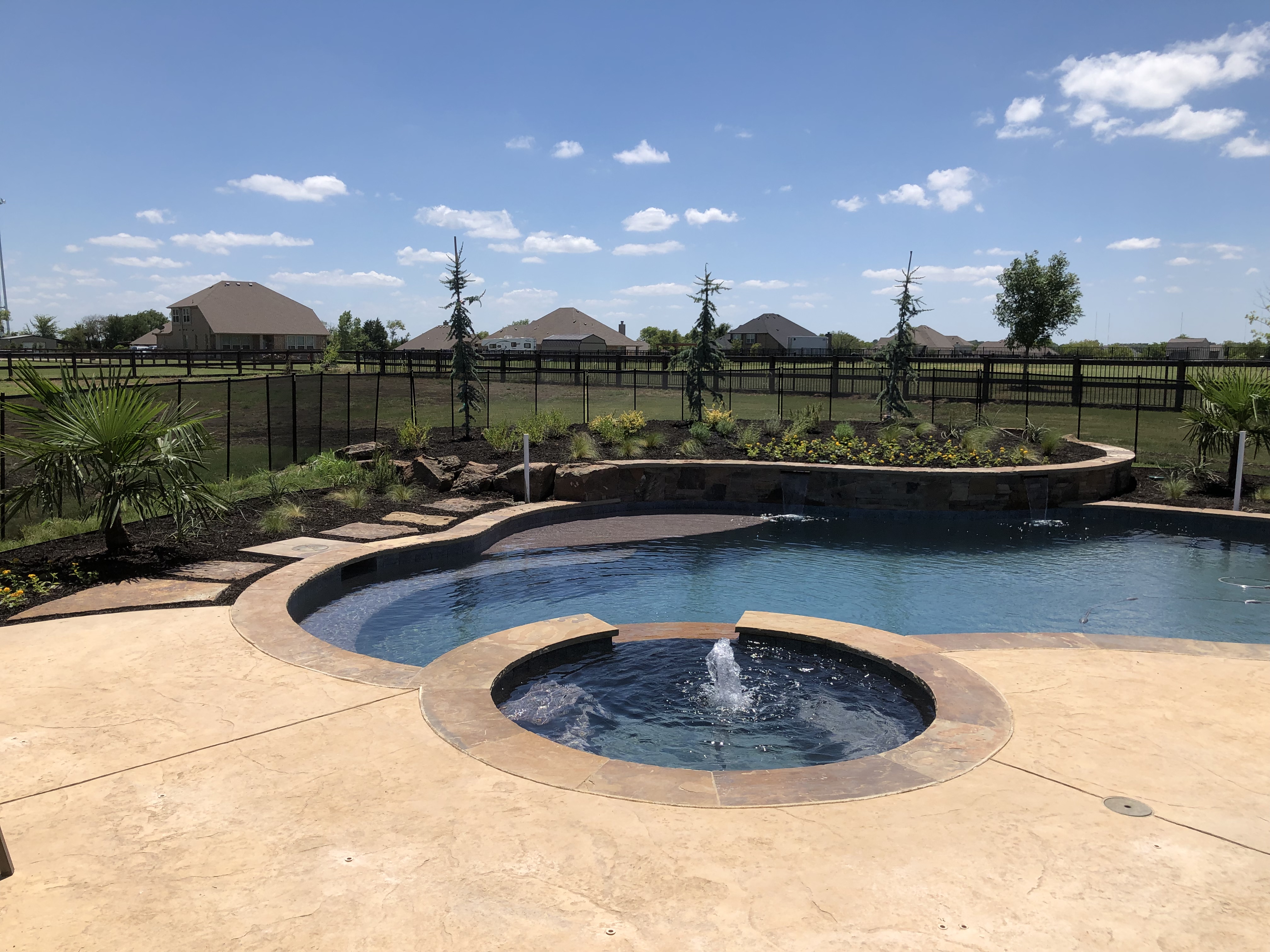 Outdoor kitchen with stone veneer, travertine patio and curved artificial turf border — Aeroscapes Landscaping Prosper TX