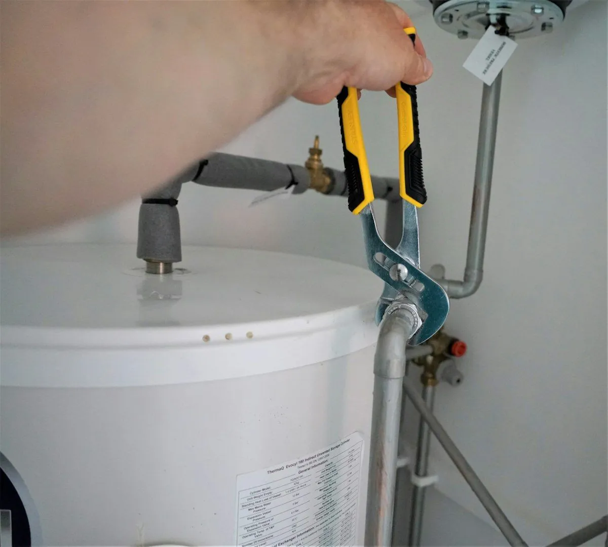 A wrench tightening a fitting on top of a water heater