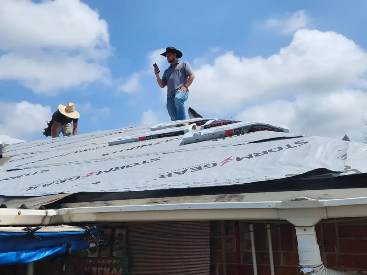 Two roofers standing on a roof wrapped in synthetic underlayment