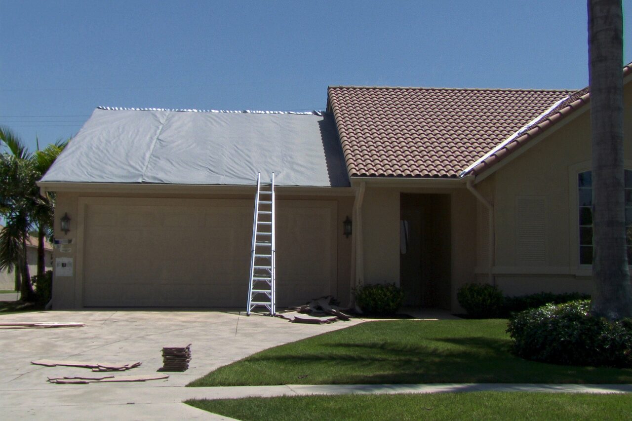 Single-story home mid re-roof with a ladder and protective covering