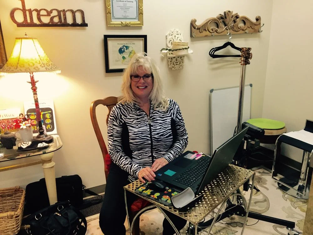 Bonnie of Coastal Thermography sits at her desk, taking the time to educate clients and answer questions before their thermography appointment.