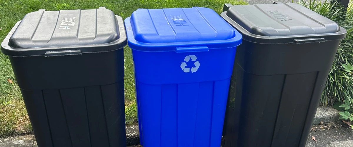 Blue recycling bin between two trash containers Blue recycling bin between two trash containers