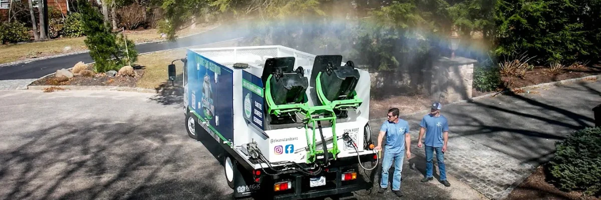 Trash bin cleaning truck spraying water with rainbow mist during sanitation service.