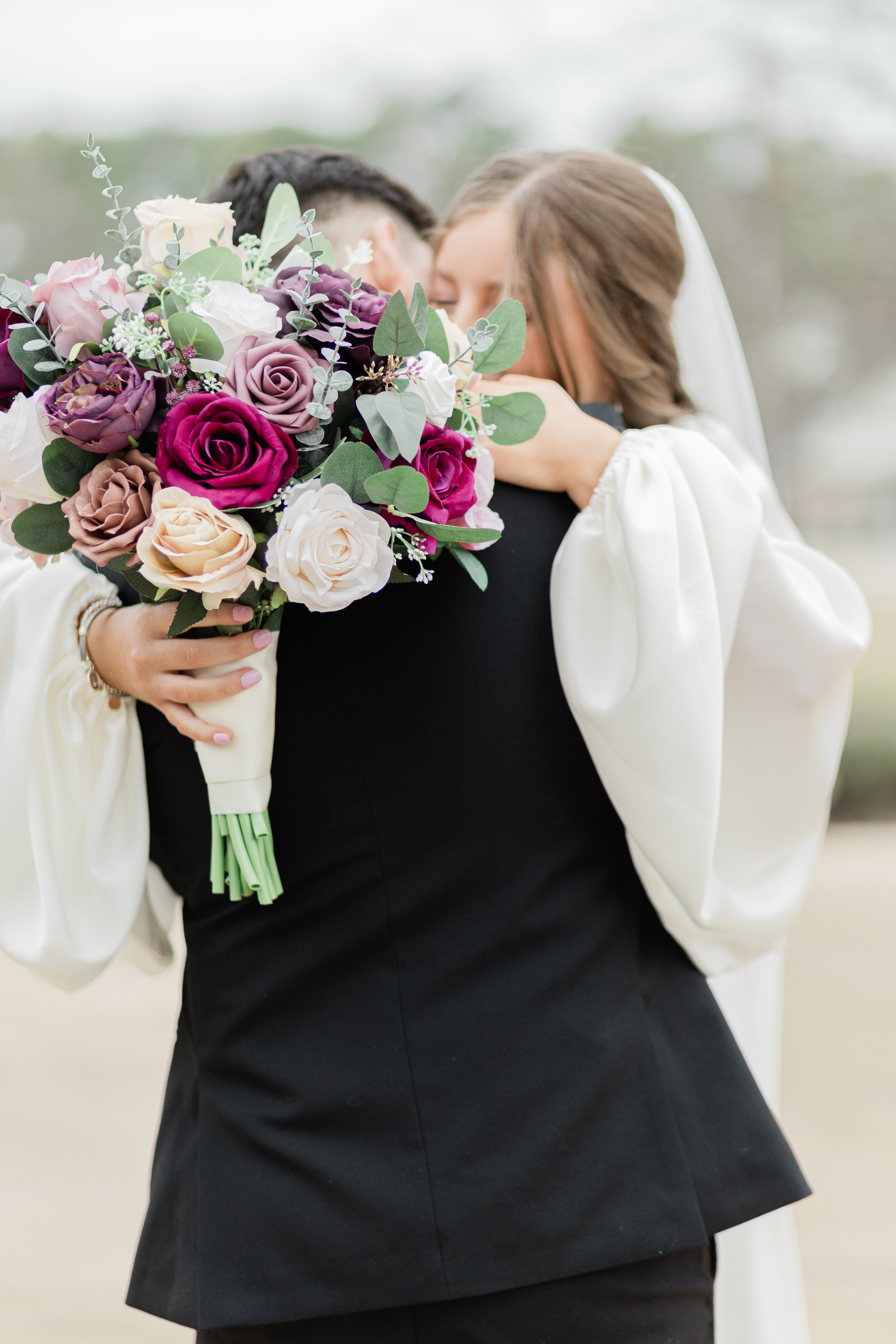 Bride is standing at bottom of curved staircase leaning over the handrail to kiss her groom at The Lone Star Mansion in Burleson Tx.