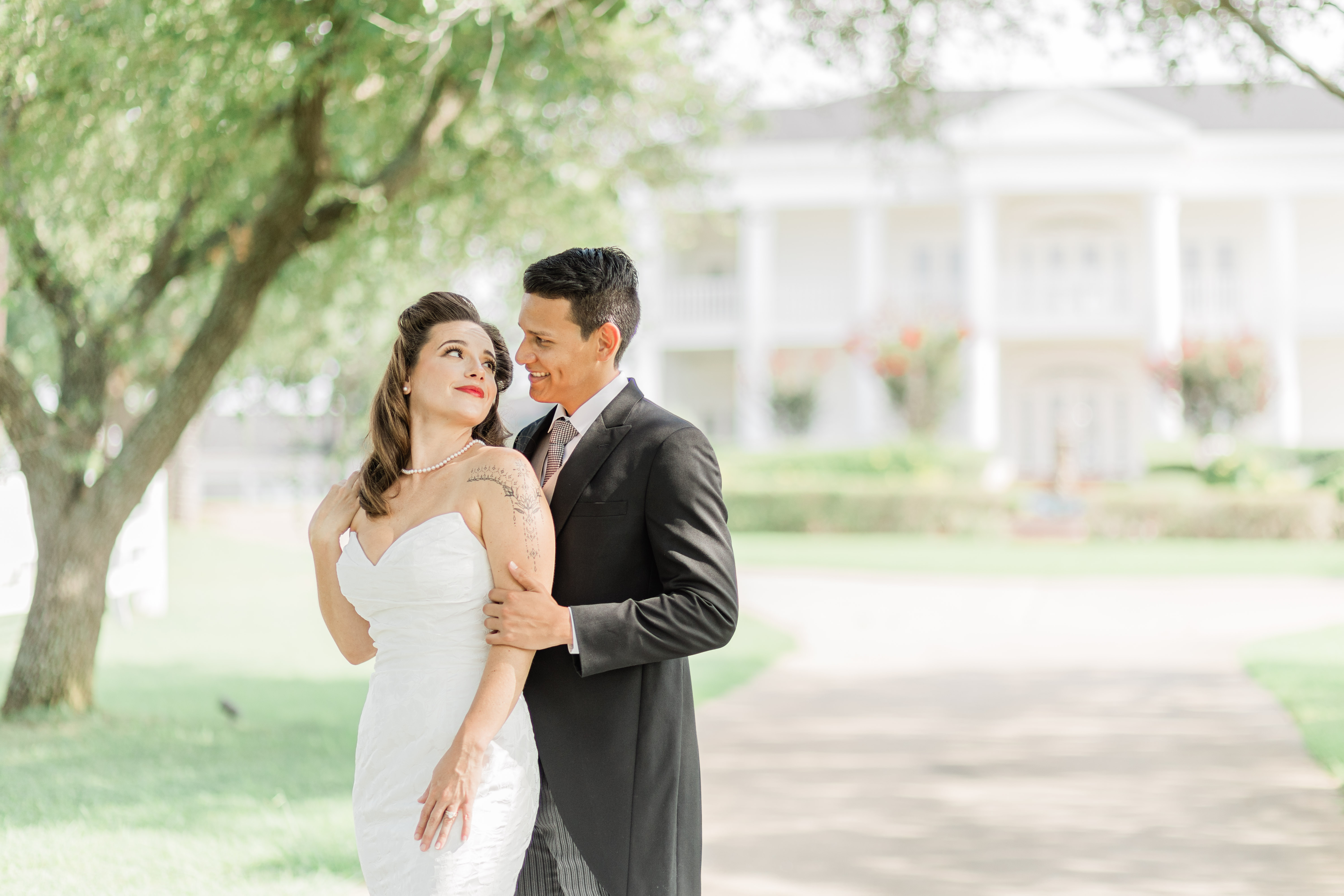 Picture of a bride and her groom in an embrace in the front tree lined entrance at Lone Star Mansion in Burleson, Tx. Image by Arlene Stepanian Photography wedding photography in Dallas and Fort Worth.