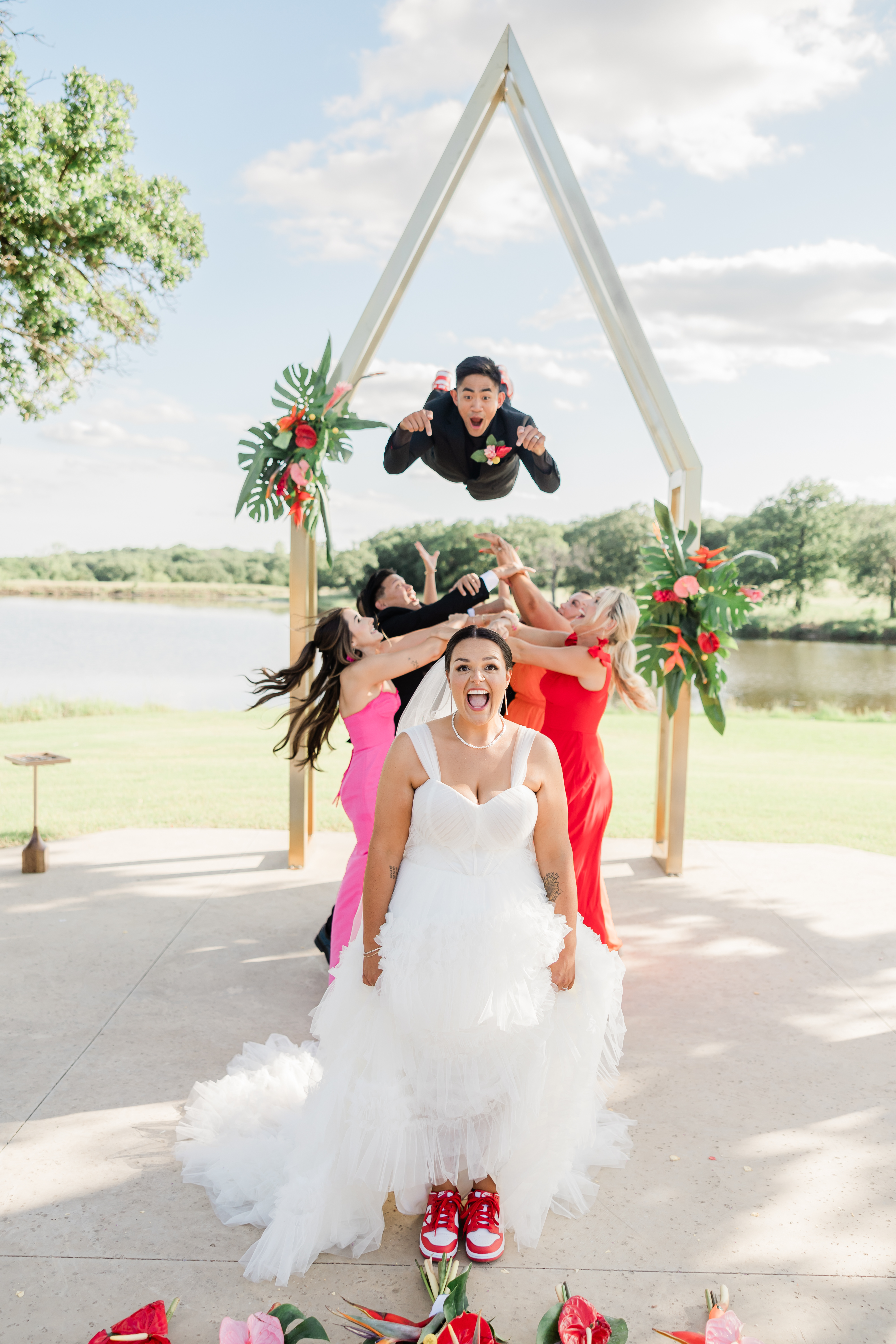A groom cradling his wife in his arms as he swings her around on the lush green lawn of The Cascades Country Club.