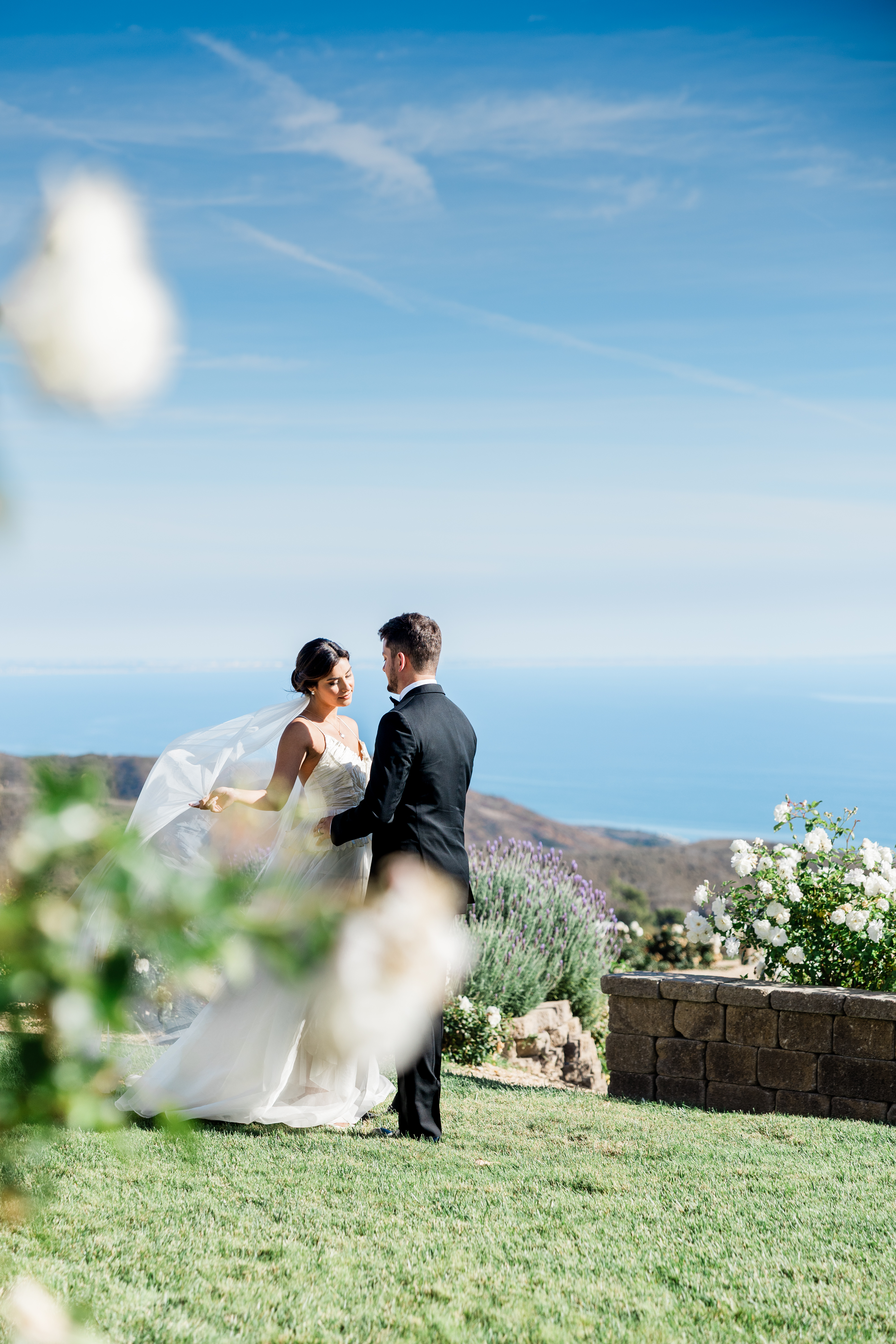 Editorial wedding portrait of bride and groom overlooking the ocean during a refined destination-style wedding day.