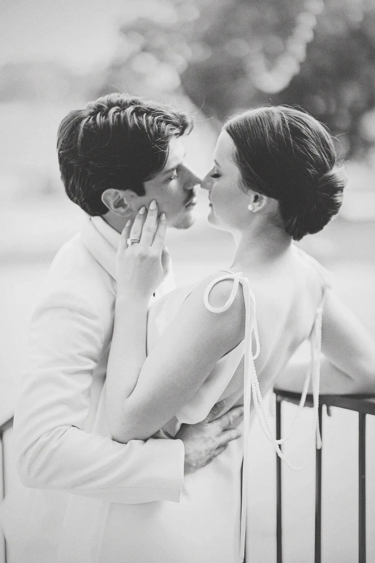 Black and white engagement photo of a couple leaning in for a soft, romantic kiss.