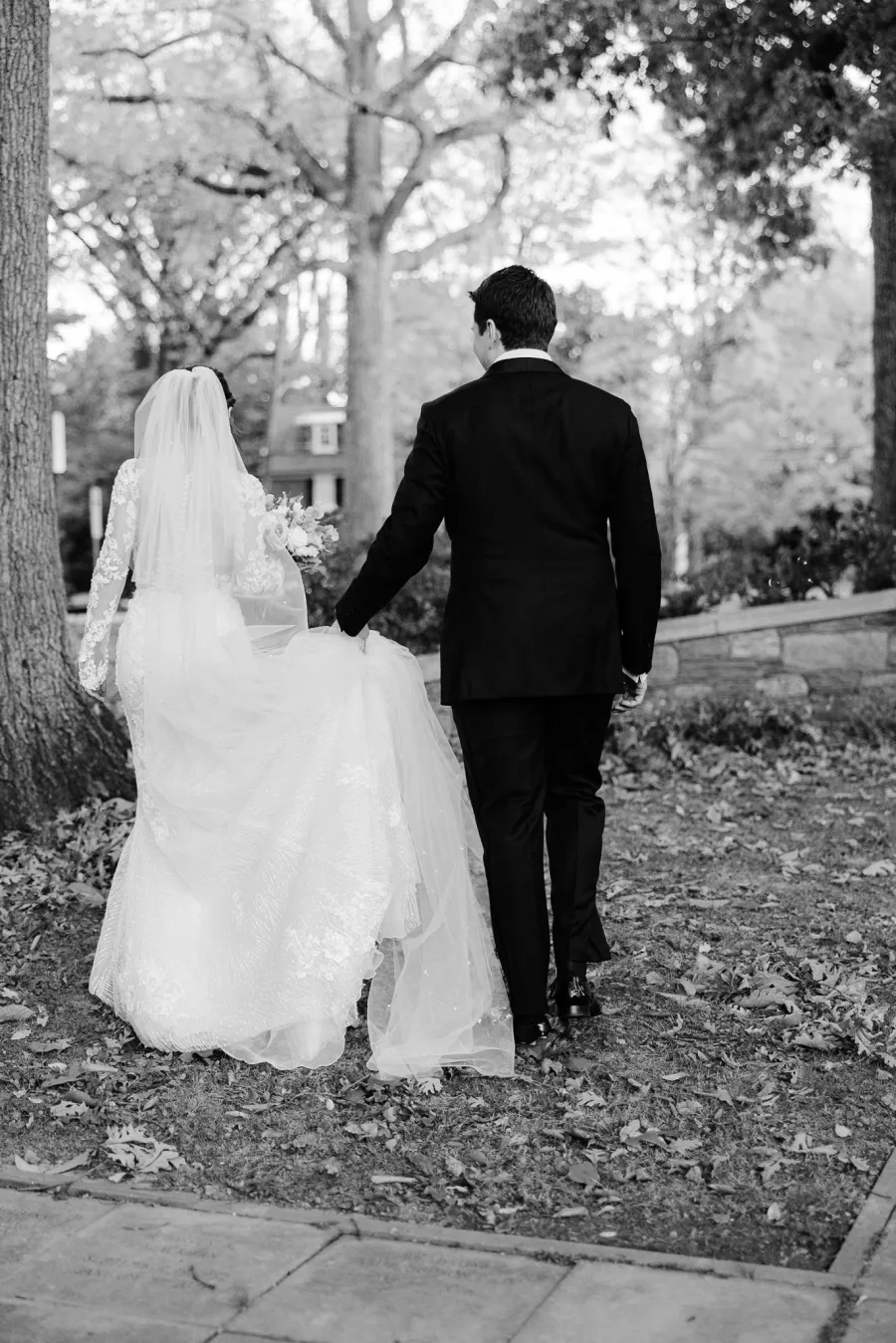 Black and white wedding portrait of bride and groom walking hand in hand after the ceremony.