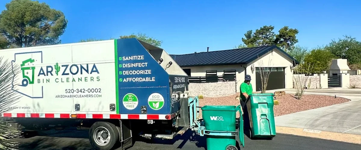 A large white and blue Arizona Bin Cleaners truck parked in front of a house, servicing two green trash cans.