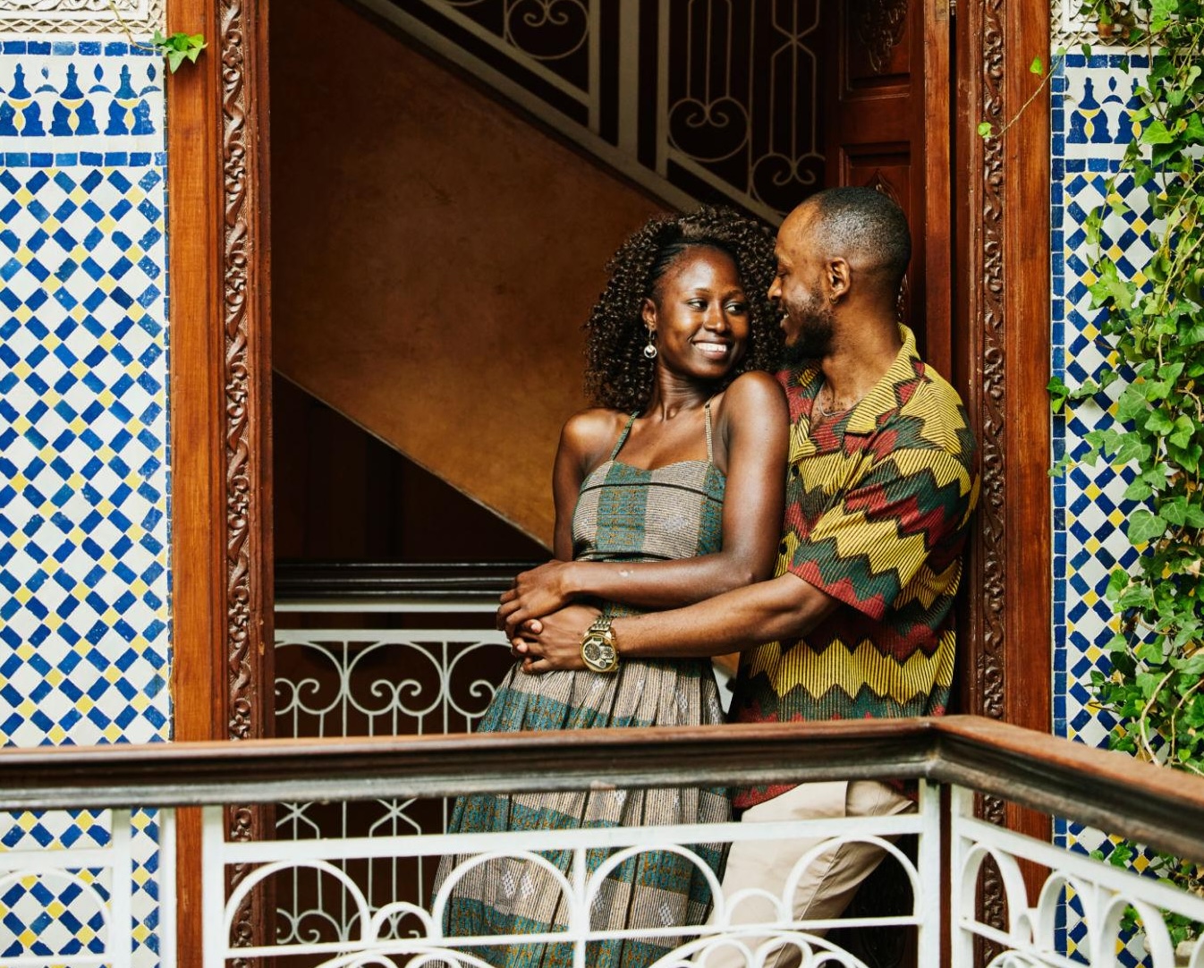 Wide shot smiling couple in doorway of ornately decorated riad