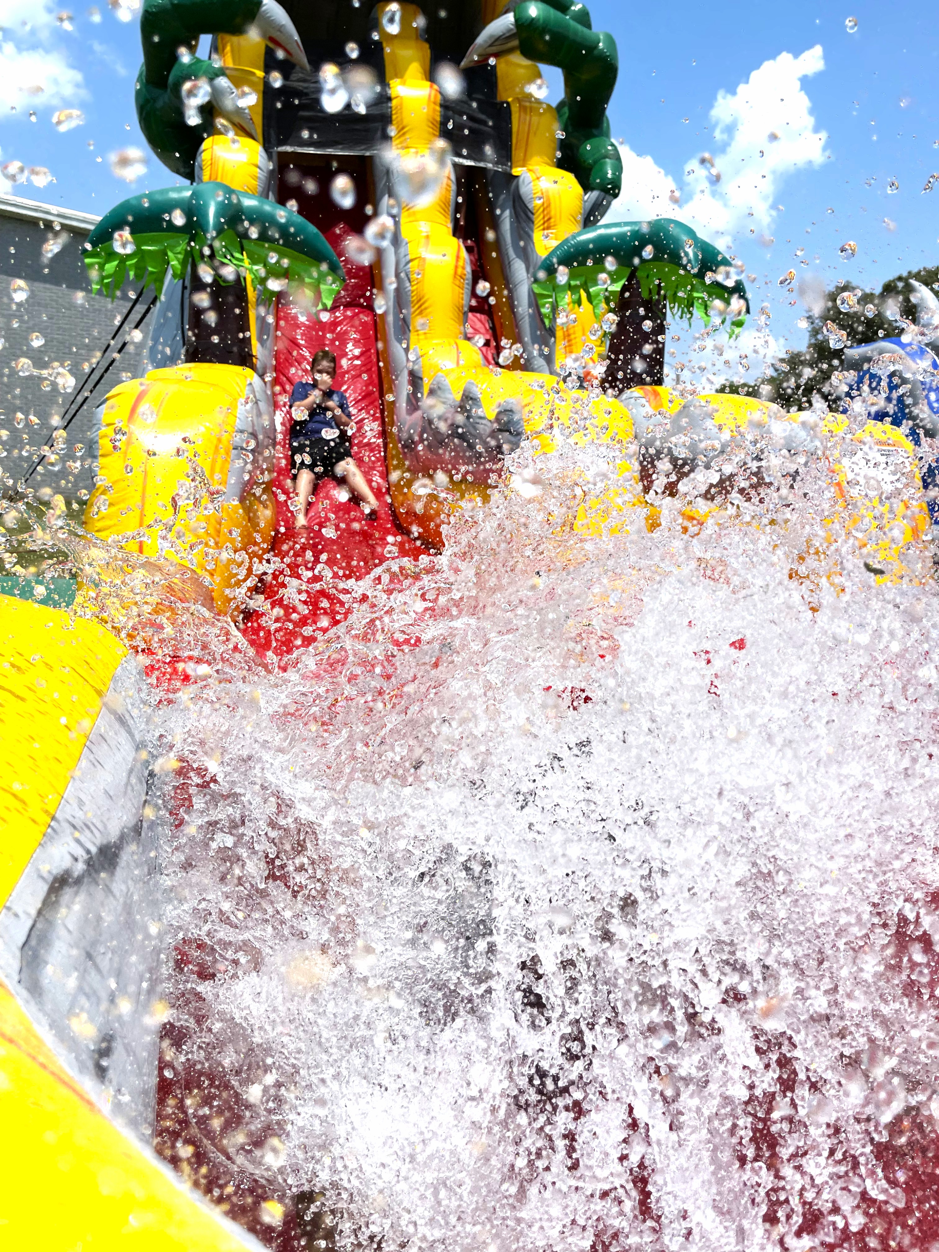 Kids sliding down a colorful inflatable water slide in Bartlett