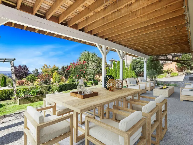 Solid wood patio cover with exposed rafters and posts shading an outdoor dining area