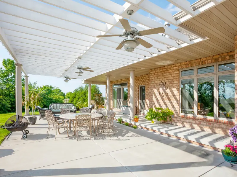Attached lattice patio cover with tightly spaced slats and ceiling fans over a brick patio