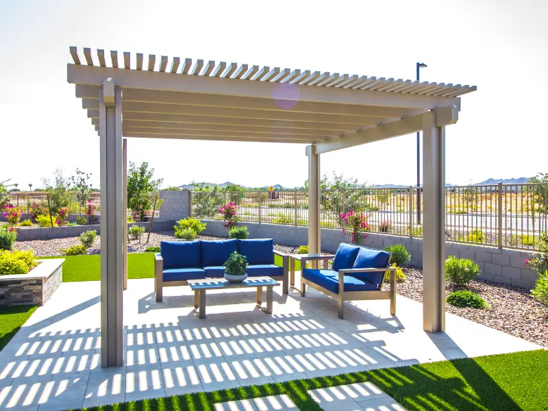 Freestanding lattice patio cover casting striped shade over a paved seating area