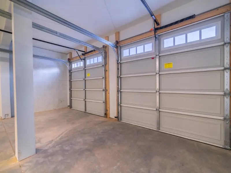 Interior view of an unfinished two-car garage with paneled doors. Interior view of an unfinished two-car garage with paneled doors.